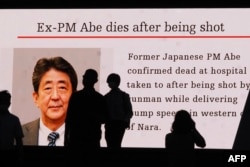 Siluet pejalan kaki di depan layar video publik besar yang menampilkan gambar mantan perdana menteri Jepang Shinzo Abe di distrik Akihabara Tokyo pada 8 Juli 2022. (Foto: AFP)