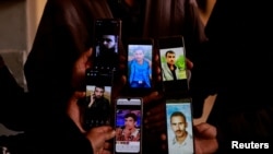 People display the photos of their relatives on mobile phones as they join members of the Syrian civil defense group, known as the White Helmets, in search of prisoners at the Sednaya prison, in Sednaya, Dec. 11, 2024.