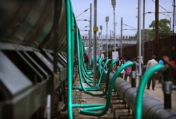 In this July 17, 2019, photo, hose-pipes are used to fill train wagons with drinking water piped in from the Mettur dam on the Cauvery River, at Jolarpet railway station, about 216 kilometers (135 miles) from Chennai.