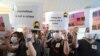 FILE - Supporters of a Hong Kong journalist fined for accessing a public database for an investigative report hold placards outside a court in Hong Kong, April 22, 2021. 