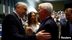 FILE - Craig Reedie, head of the World Anti-Doping Agency (WADA), right, welcomes Yuri Ganus, Russian Anti-Doping Agency (RUSADA) director general, at the WADA Symposium in Ecublens, near Lausanne, Switzerland, March 21, 2018.
