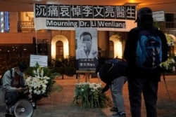 FILE - People attend a vigil for Chinese doctor Li Wenliang, in Hong Kong, Feb. 7, 2020. Li, who got in trouble with authorities for sounding an early warning about the coronavirus outbreak, died after being infected.