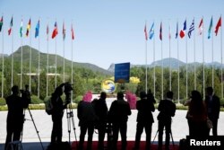 FILE - Journalist take pictures outside the venue of a summit at the Belt and Road Forum in Beijing, China, May 15, 2017.