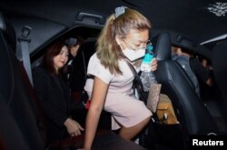 Sararat Rangsiwuthaporn, a suspect in over a dozen murders, is escorted by police officers at a police station in Bangkok
