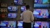 A salesman watches Prime Minister Narendra Modi addressing to the nation, on TV screens inside a showroom in Mumbai, India, March 27, 2019. 