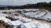 FILE - Refugees and migrants make their way in the Kara Tepe camp on the island of Lesbos