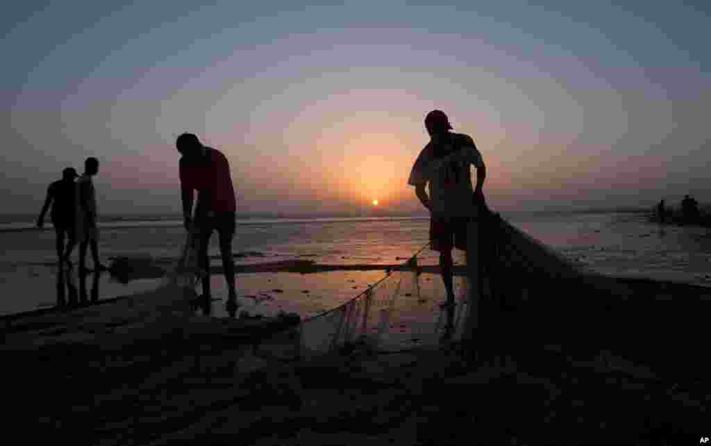 Pakistani fishermen sort out their nets at sunset on the coast of the Arabian Sea, in Karachi.