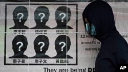 Seorang mahasiswa menempelkan poster menuntut pembebasan 12 aktivis Hong Kong yang ditahan oleh pihak berwenang China, di "Dinding Lenon", di Universitas Hong Kong, 29 September 2020.