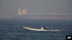 A fishing boat speeds past an oil tanker in the distance in Fujaira, United Arab Emirates, June 15, 2019. The Kokuka Courageous, one of two oil tankers targeted in apparent attacks in the Gulf of Oman, was brought to the United Arab Emirates' eastern coa
