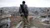 FILE - A Syrian Kurdish sniper looks at the rubble in the Syrian city of Kobani.