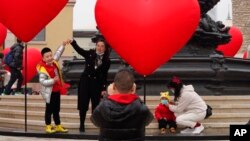FILE - Families with young children pose for photos in Beijing, China, Feb. 13, 2021. Struggling with an aging population and declining birth rates, China is trying to shift its population policies to avert a demographic crisis.