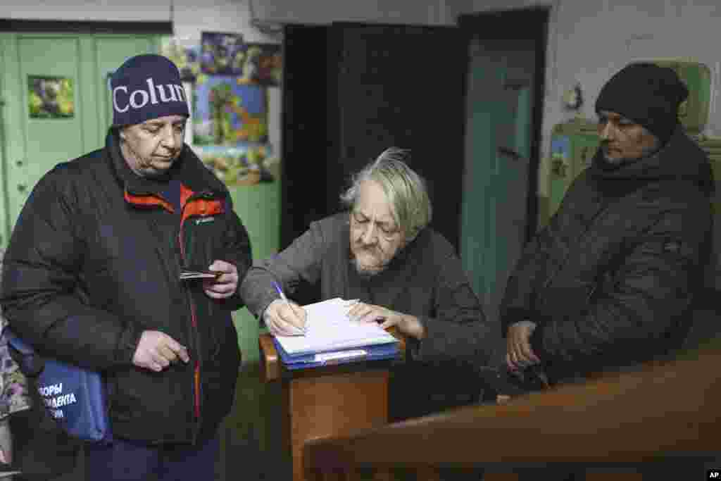 Чоловік розписується у бюлетені під час президентських виборів у Росії. Мобільна виборча комісія відвідує тих людей, які не можуть самостійно дійти до виборчих дільниць, у сибірському місті Омськ, 2236 км на схід від Москви, Росія, п’ятниця, 15 березня 2024 року. (Фото: AP Photo)