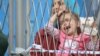 At a temporary refugee camp in Opatovac, Croatia, families complain they have been separated from relatives as children are passed back and forth over a fence, Sept. 22, 2015. (Heather Murdock/VOA)