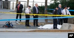 Authorities investigate the scene around a body covered under a white sheet next to a mangled bike along the bike path, Oct. 31, 2017, in New York.