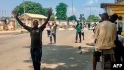TOPSHOT - People are obliged to walk with their hands upon their heads as they pass security checkpoints, held by security forces wearing civil clothes and holding machetes and sticks to control the crowd, at Obalende Market, Lagos, Nigeria, on…