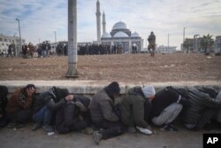 Government soldiers and their allies huddle on the ground while being detained by insurgents in Homs, Syria, Dec. 8, 2024.