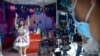 Seorang perempuan merekam video di dekat logo aplikasi Bilibili dan Douyin di sebuah stan dalam pameran telekomunikasi di Beijing, China, pada 28 September 2021. (Foto: AP/Mark Schiefelbein)