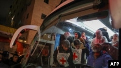 Палестински затвореници (позади) чекаат да се симнат од автобус на Црвениот крст по нивното пристигнување во окупираниот град Беитунија на Западниот Брег, на периферијата на Рамала, по нивното ослободување од Израел во раните часови на 20 јануари 2025 година.