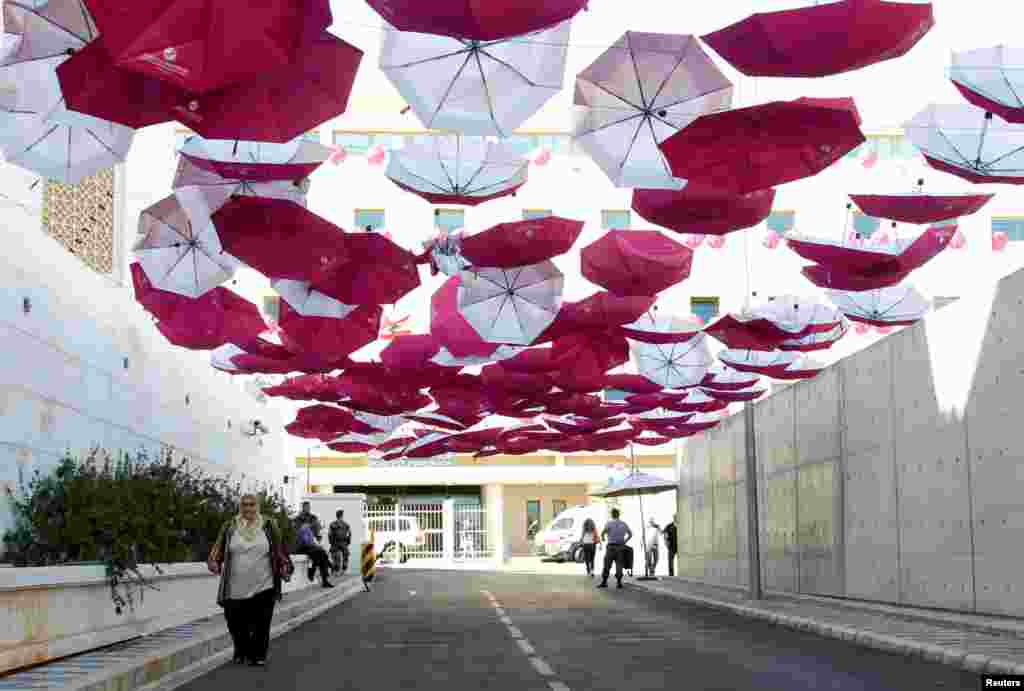 A woman walks under a canopy of umbrellas erected outside the Ministry of Public Health, part of a campaign aiming at raising awareness of breast cancer prevention, in Beirut, Lebanon.