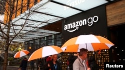 People walk by the entrance to the new Amazon Go store at Amazon's Seattle headquarters in Seattle, Washington,