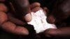 FILE - A Congolese mineral trader holds a piece of paper containing nuggets of gold in a mud hut at Numbi in eastern Congo.