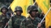 FILE - Hezbollah fighters hold their group's flags at a rally in Nabatiyeh, southern Lebanon, Nov. 7, 2014.