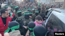 Anggota militan Hamas menyerahkan Doron Steinbrecher, yang sebelumnya mereka sandera, sebagai bagian dari pertukaran sandera dan tahanan dalam kesepakatan gencatan senjata Israel-Hamas di Gaza, pada 19 Januari 2025. (Foto: Reuters/via Reuters TV)