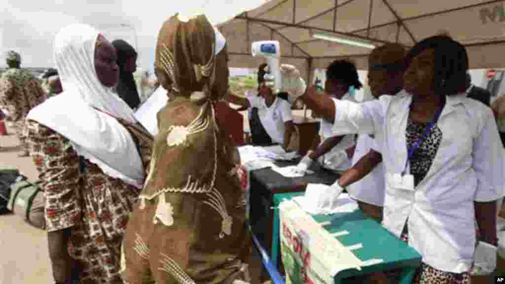 Wani jami’in kula da lafiyar matafiya na amfani da ma’aunin zafin jiki ya na yiwa Maniyyata gwajin cutar Ebola a ranar goma sha takwas ga watan satumba shekarar dubu biyu da goma sha hudu, 18 ga Satumba, 2014.