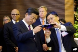 Harry Shum (kanan) Wakil Presiden Eksekutif Microsoft bidang Riset dan Teknologi menmperlihatkan HoloLens Micosoft kepada Presiden China Xi Jinping (kiri) dalam kunjungannya di kampus Microsoft di Redmond, Washington (23/9).