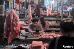FILE - Vendors at their pork stalls at a market in Hekou Yao Autonomous County, Yunnan province, China, May 3, 2019.