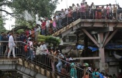 FILE - Commuters walk on an overbridge at a train station in Mumbai, India. India's labor-intensive manufacturing sector growth slipped to 5% in the April-June quarter, the slowest pace in six years, July 5, 2019.