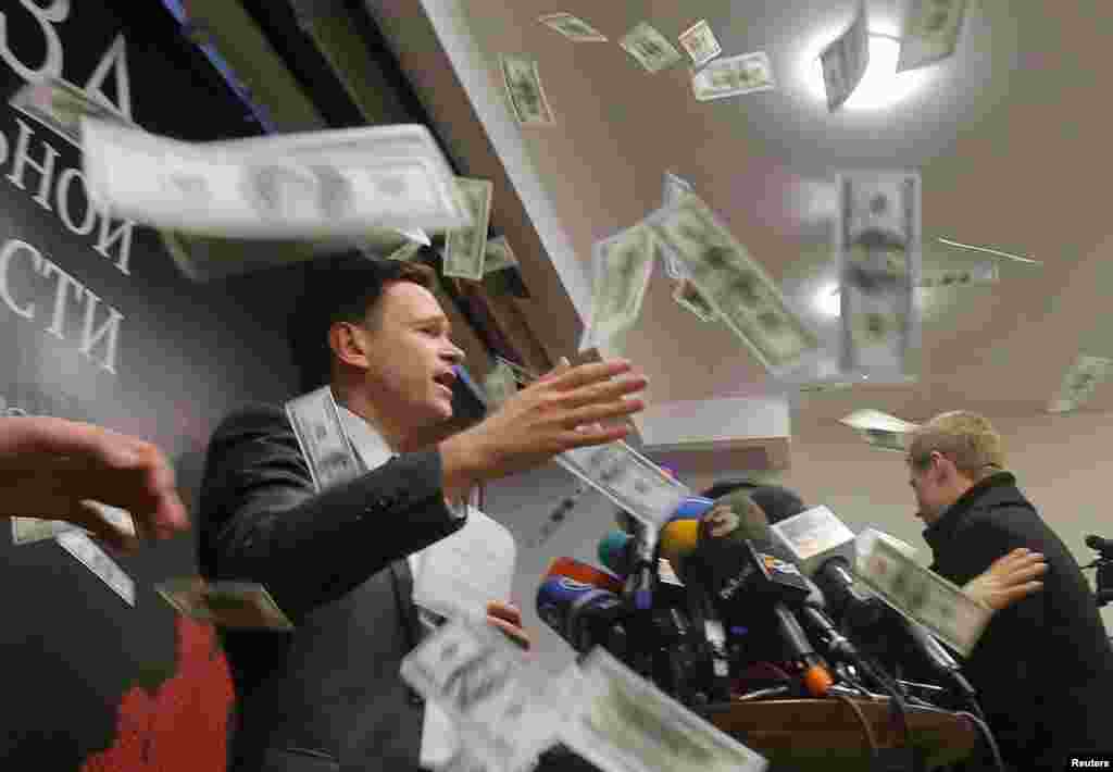 An unidentified person throws pieces of paper resembling banknotes, as Russian opposition figure Ilya Yashin (L) presents his report, titled 'National Security Threat' and dedicated to the current situation in Chechnya and its leader Ramzan Kadyrov, in Moscow.