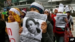 Domestic helpers and their supporters hold pictures of 23-year-old Indonesian maid Erwiana 