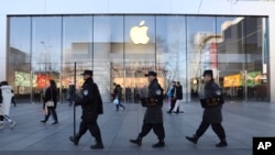 Chinese security guards march past an Apple store in Beijing, China, March 6, 2019.
