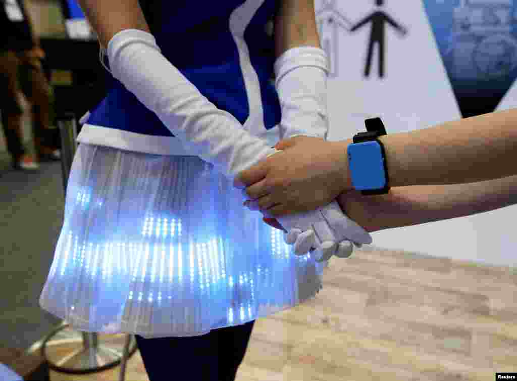 Women demonstrate Panasonic's Human Body Communication Device, which changed color of LEDs on a cloth to same color of wrist device at CEATEC (Combined Exhibition of Advanced Technologies) JAPAN 2016 at the Makuhari Messe in Chiba, Japan.