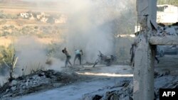 Warga Suriah menggunakan tanah untuk memadamkan api di tempat serangan udara di distrik Jisr al-Shughur, di Provinsi Idlib, 4 September 2018.