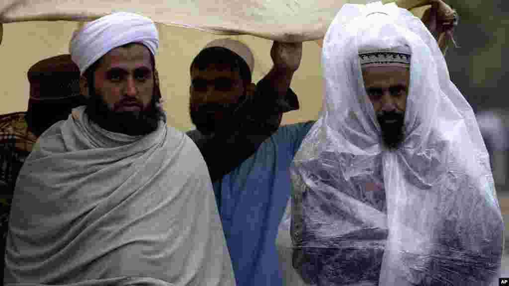 بارش سے بچنے کے لیے ایک شخص نے پلاسٹک کی شیٹ اوڑھی ہوئی ہے۔ 