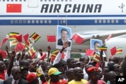 Zimbabweans wave flags while welcoming Chinese President Xi Jinping in Harare, Zimbabwe, Tuesday, Dec. 1, 2015.