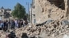 FILE - Residents look at the damage by what activists said was a barrel bomb dropped by forces of Syria's President Bashar al-Assad, in the old city of Aleppo, May 31, 2015.