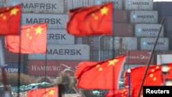 Кинеските национални знамиња се веат во близина на бродските контејнери во пристаниште надвор од Шангај, 7 февруари 2025 година