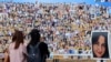 Pengunjung warga Israel memperhatikan foto-foto orang-orang yang disandera atau terbunuh dalam serangan oleh Hamas terhadap festival musik Supernova pada 7 Oktober 2023, dekat Kibbutz Rein di selatan Israel, 10 April 2024. (Foto: Jack Guez/AFP)