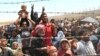 FILE - Syrian refugees gather at the Turkish border as they flee intense fighting in northern Syria between Kurdish fighters and Islamic State militants in Akcakale, southeastern Turkey, June 15, 2015.