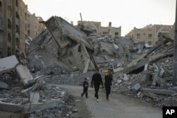 File - Anak-anak muda Palestina berjalan di antara puing-puing bangunan yang hancur di sebuah kawasan Khan Younis, Jalur Gaza, Minggu, 1 Desember 2024. (Abdel Kareem Hana/AP)