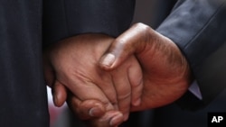The hand of Chinese President Xi Jinping, left, holds the hand of Zimbabwean President Robert Mugabe, upon his arrival in Harare, Zimbabwe, Tuesday, Dec. 1. 2015