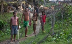 Indian children stand by a fence on the India-Bangladesh border at Jhalchar, in the northeastern Indian state of Assam.