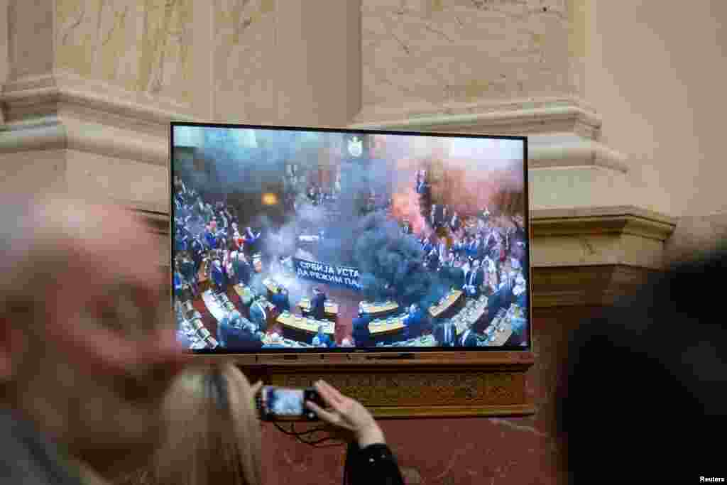 Новинарите го гледаат преносот во живо додека пратениците на опозицијата фрлаат димни бомби парламентот, во Белград, Србија.