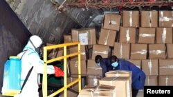 Seorang anggota tim medis mengenakan baju pelindung menyemprotkan kargo medis yang baru tiba di dalam sebuah pesawat di Bandara Internasional Juba di Juba, Sudan Selatan, 5 April 2020.