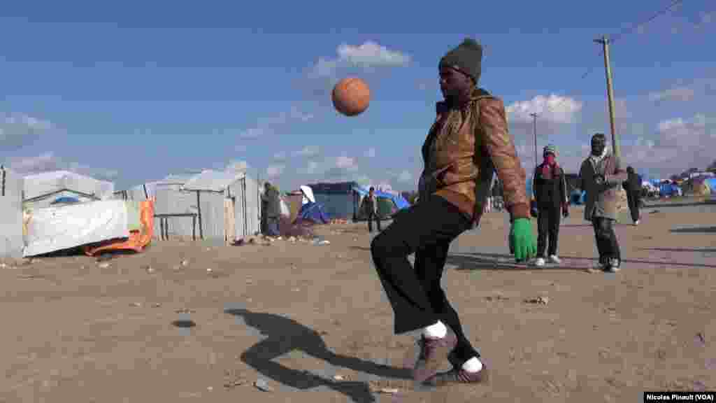 Wani dan gudun hijira ne ke wasan kwallo a sansanin dake wajen birnin Calais dake arewacin birnin Faransa. (Nicolas Pinault/VOA).