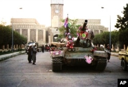 Tanks manned by Taliban fighters and decorated with flowers are shown in front of the the presidential palace, Sept. 27, 1996, in Kabul. The Islamic rebels pursued government forces Sept. 28 retreating from the devastated capital and said they had hanged two aides of the country's Soviet-era leader. The unidentified aides met the same fate as former President Najibullah and his brother, who were executed Sept. 26.