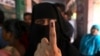 An Indian Muslim woman displays the indelible ink mark on her finger after casting her vote, outside a polling station in Chennai, India, April 18, 2019. 